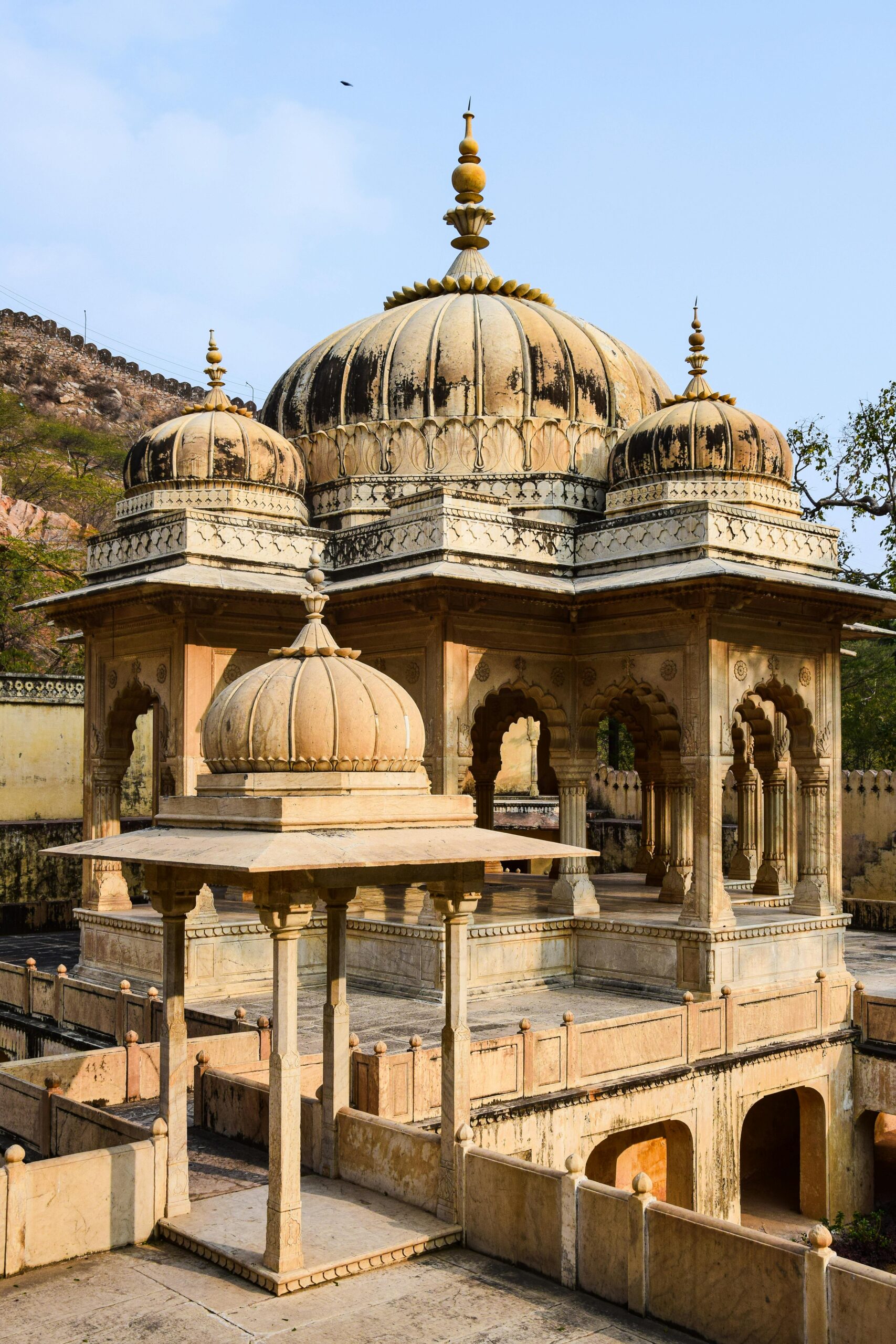Beautifully detailed architecture of Gatore Ki Chhatriyan in Jaipur, India, under a clear sky.